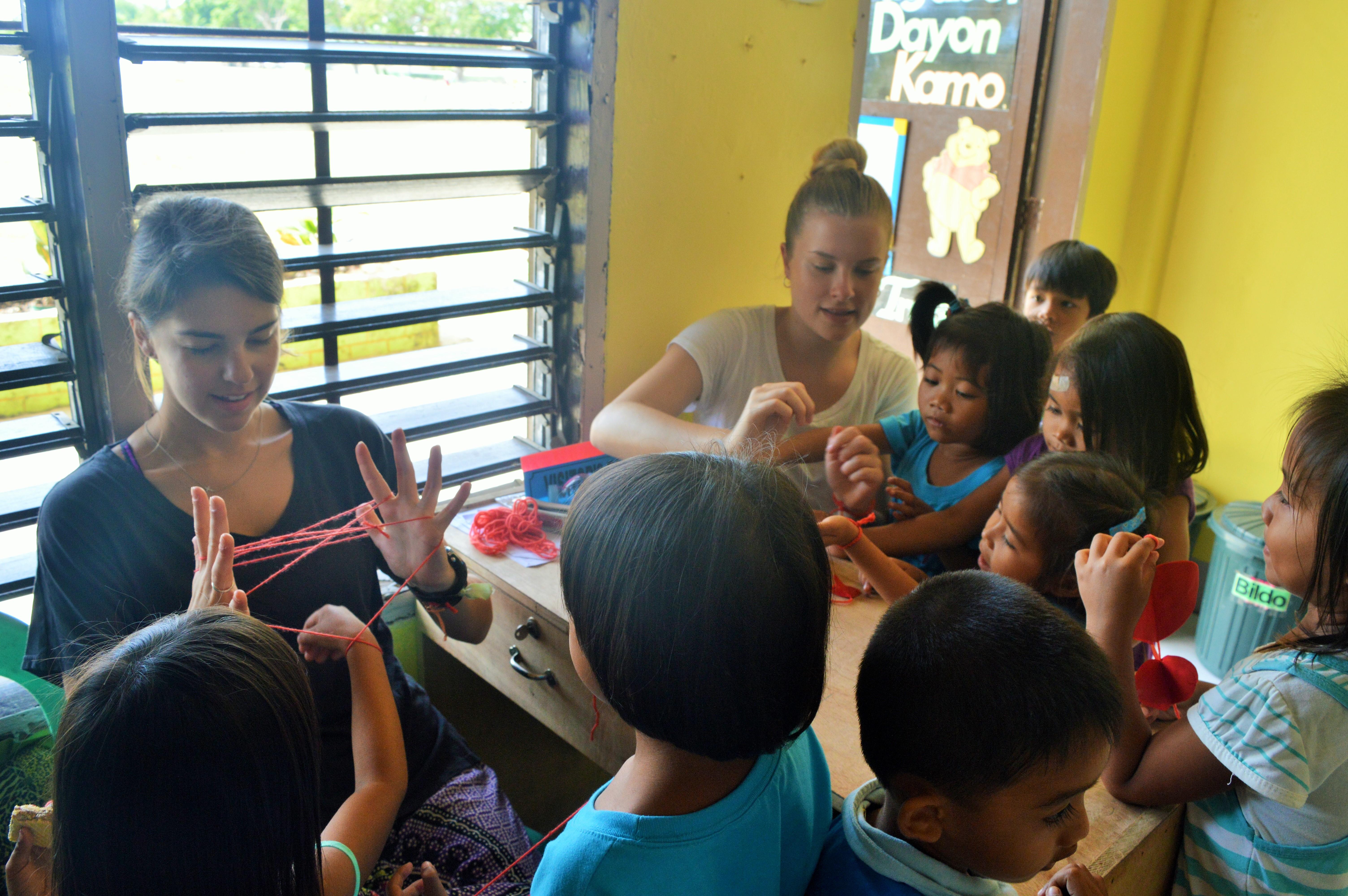 Two female Projects Abroad volunteers do arts and craft activities with a group of Filipino children at their Childcare Project. Local children use their creativity during an arts and crafts lesson run by Projects Abroad Childcare volunteers in the Philippines.